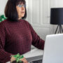 Attractive middle-aged brunette business woman works at a laptop while sitting at a table.