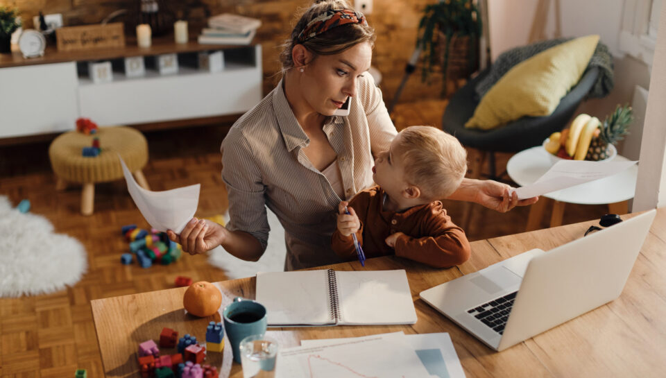 Busy mother trying to work while babysitting her small son at home.