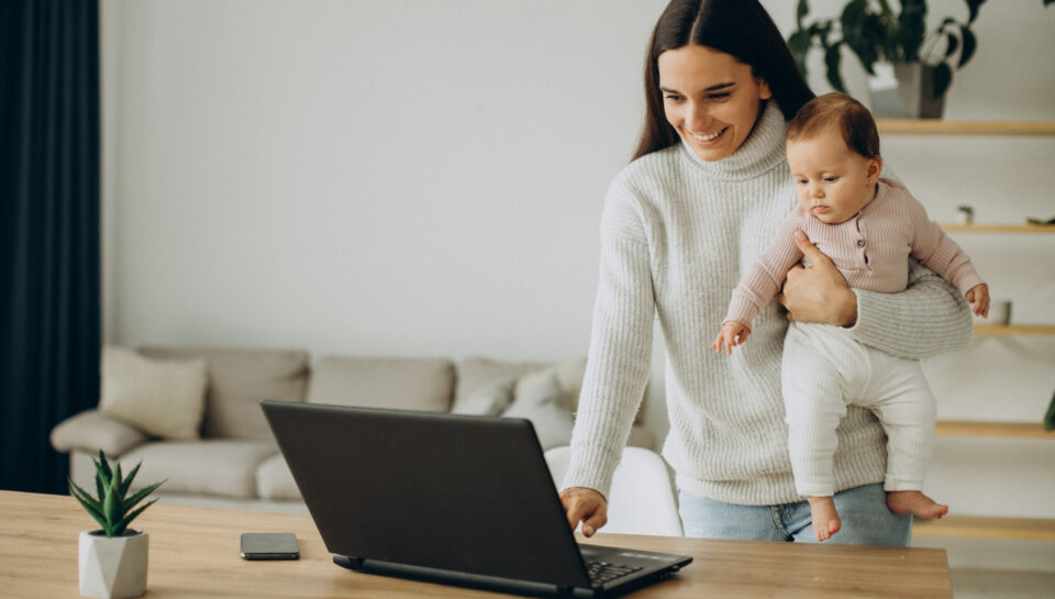 Mother with baby daughter working on computer from home