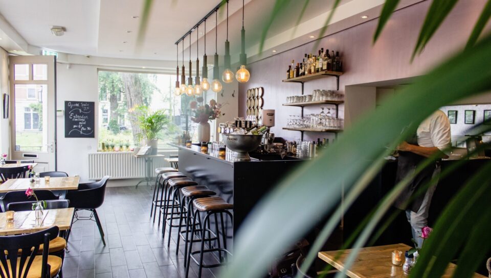 An interior shot of a cafe with chairs near the bar with wooden tables
